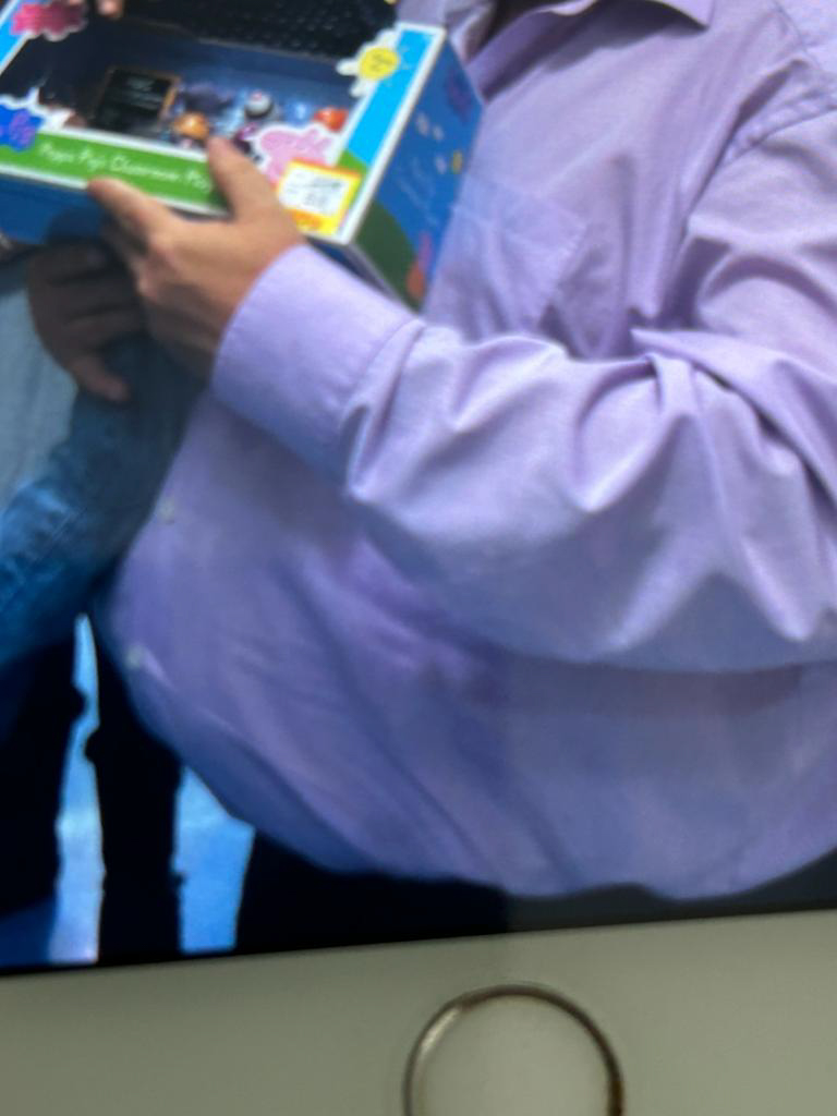 Person in a light purple shirt holding a colorful boxed toy or game.