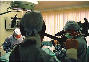 Surgical team in an operating room performing surgery with medical equipment and bright lighting.