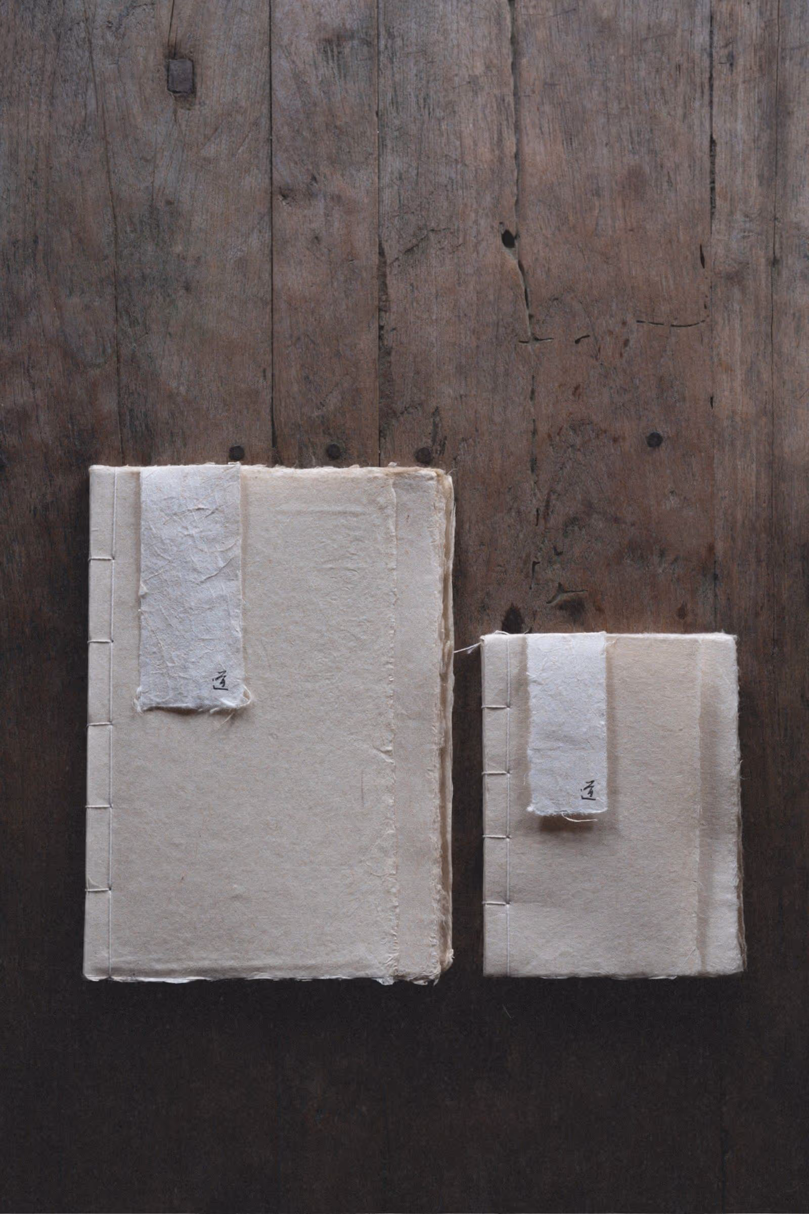 Large and small paper journals shown side by side set on a rustic wood coffeetable