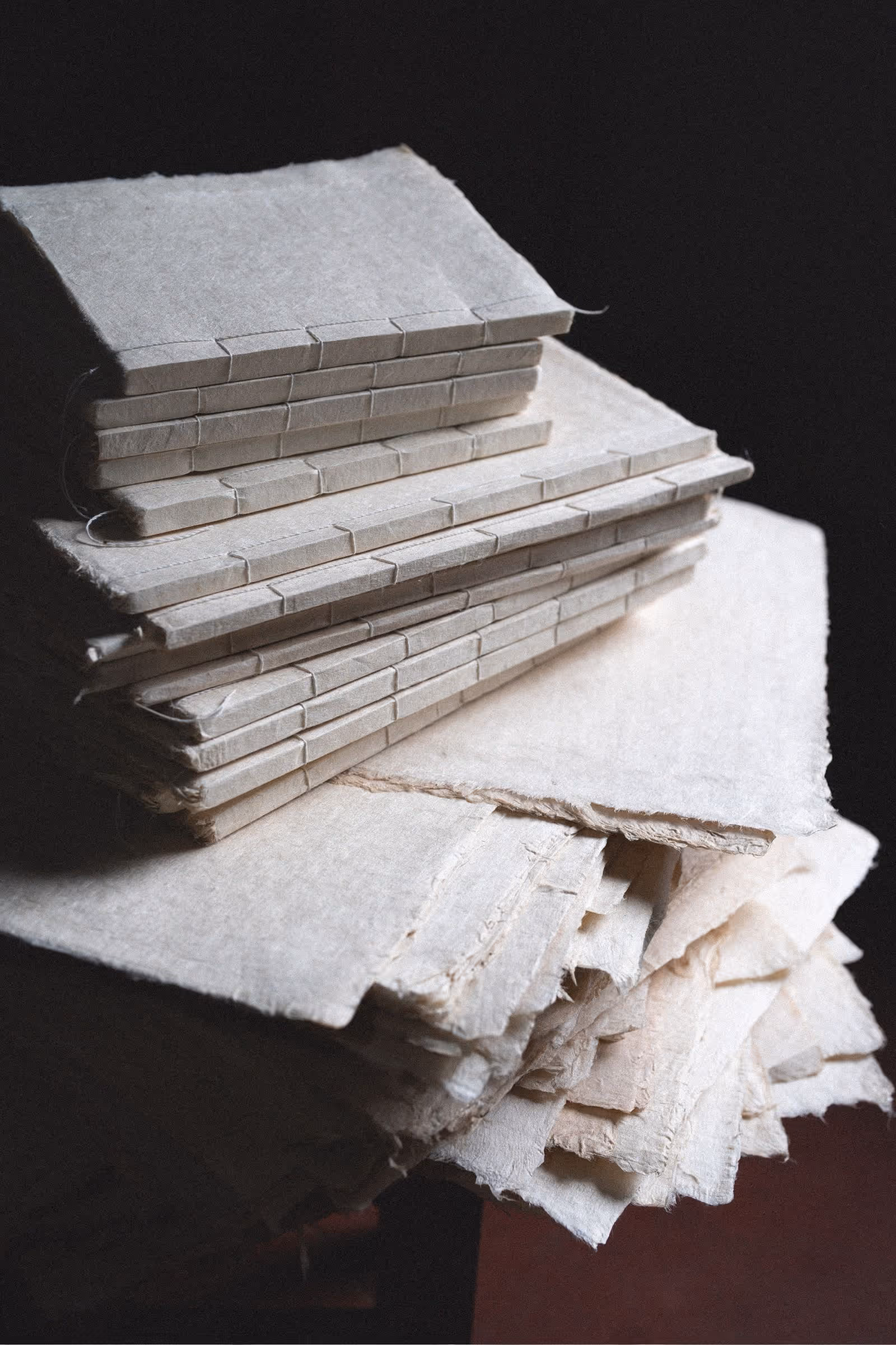 Close up detail of stack of small handmade journals with varied natural paper textures in old world setting with fine art paper texture overlay.