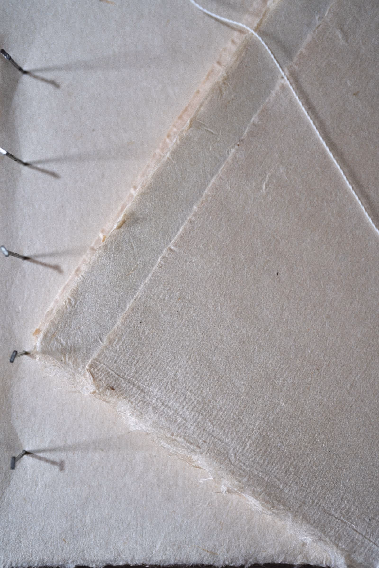 Loose artisanal paper journal displaying blank, eco-friendly pages and delicate hand-binding