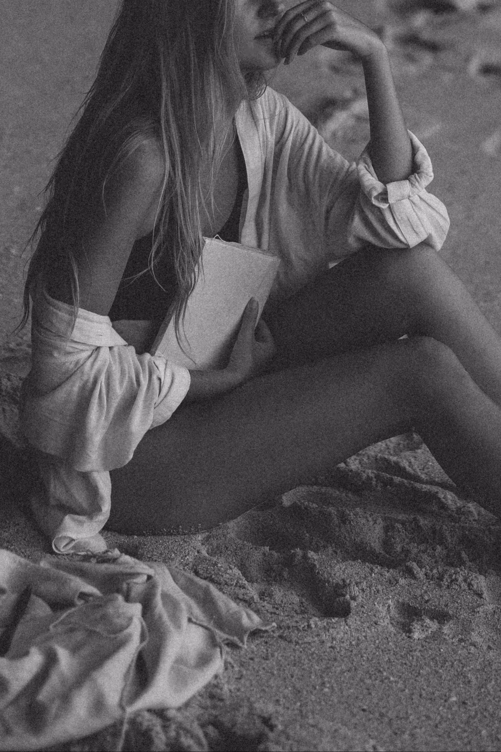 Woman holding a handmade paper journal while seated in quiet reflection, black-and-white