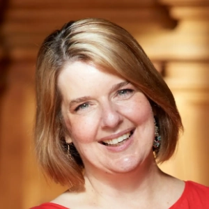 Woman with light brown/blonde hair smiling with their head tilted