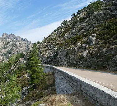 Aszfalt út halad magasan a sziklás hegyek mentén.