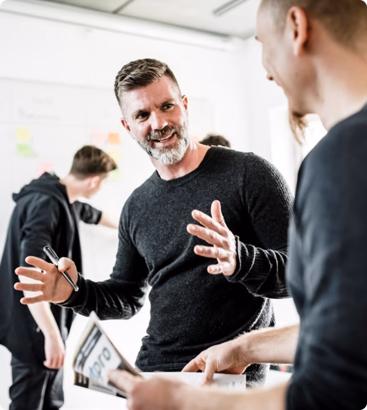 Zwei Männer führen eine lebhafte Diskussion, während eine dritte Person im Hintergrund aushilft.
