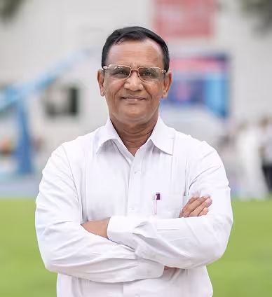 Smiling middle-aged man with glasses wearing a white shirt and crossing his arms outdoors.