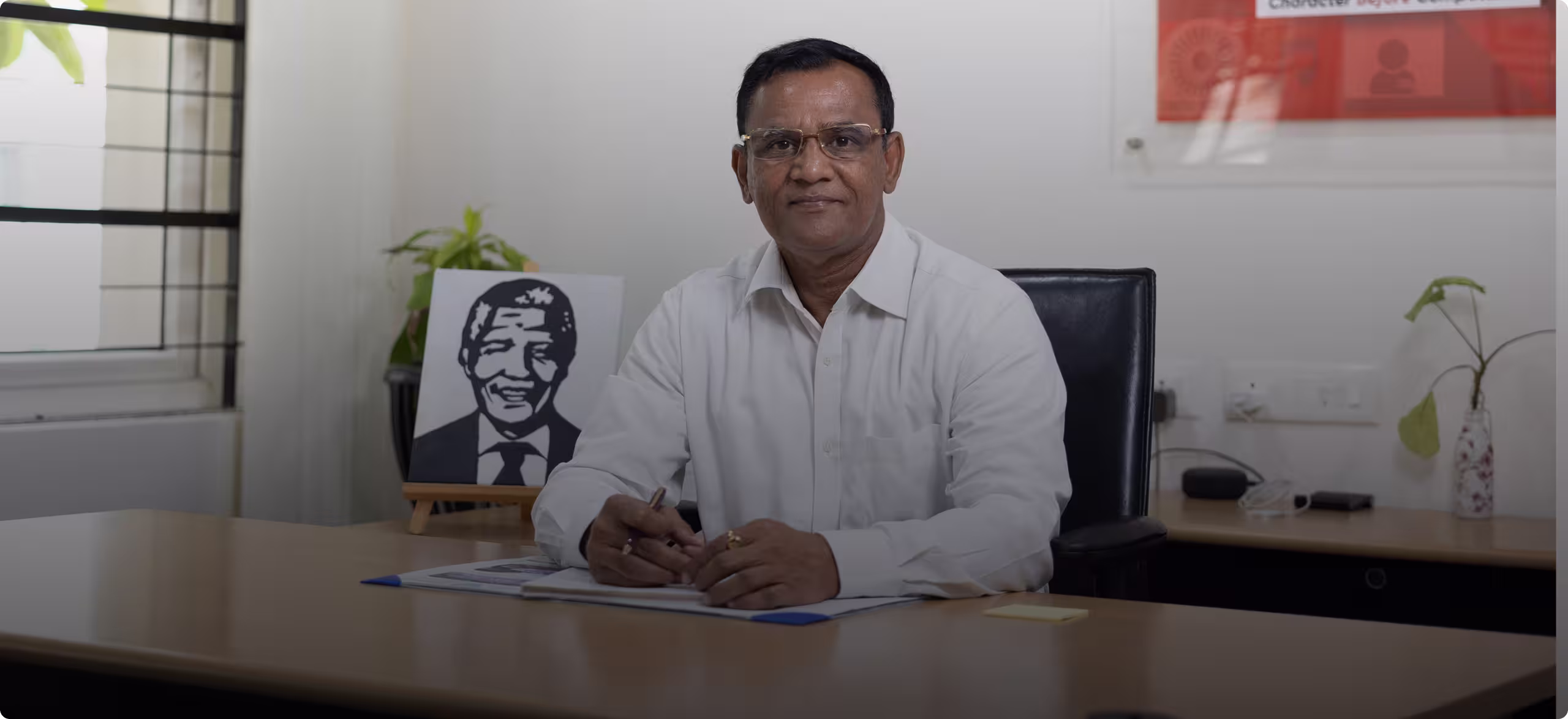 Middle-aged man wearing glasses and a white shirt stands outdoors with arms crossed, smiling.