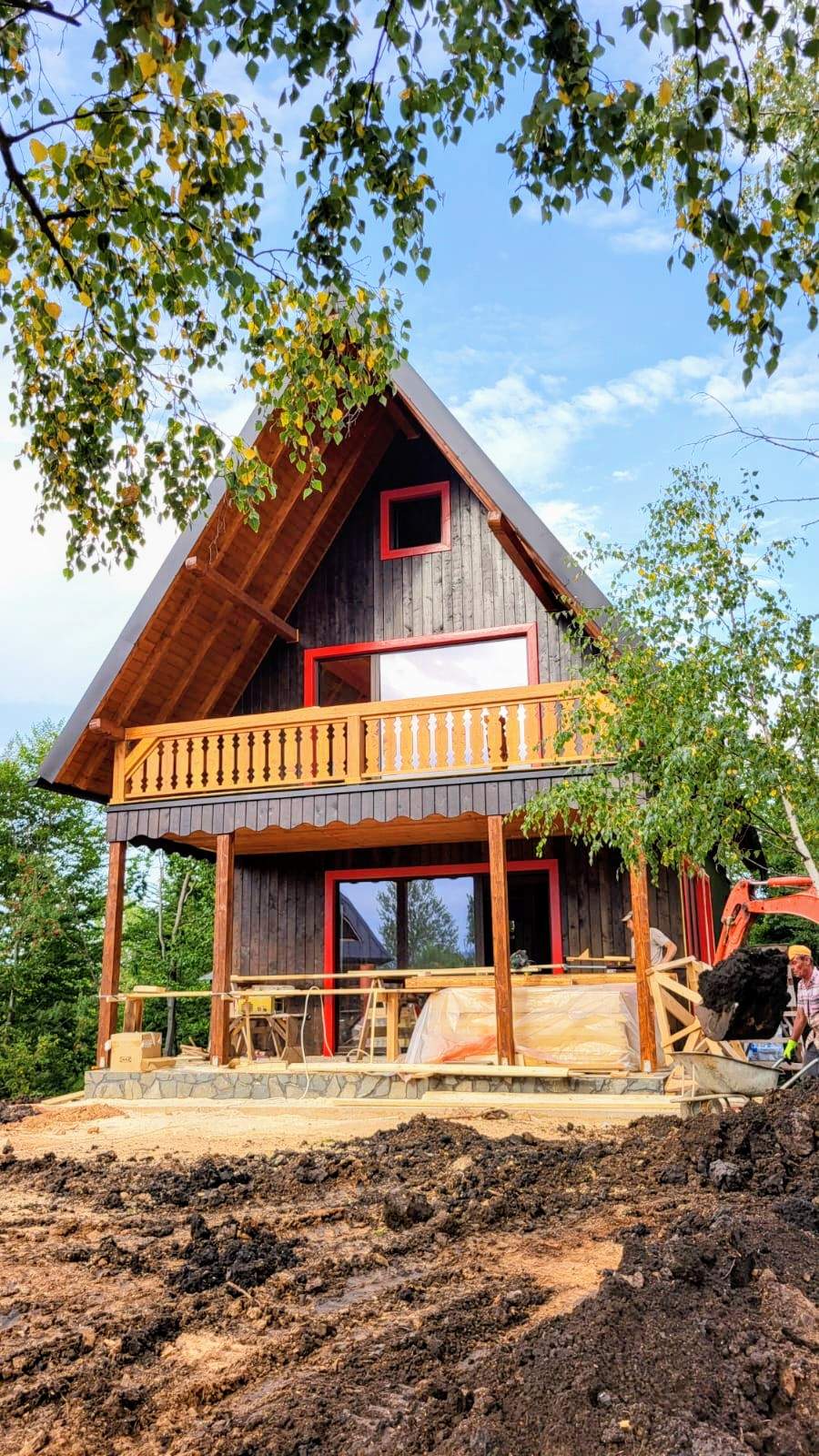 A rustic wooden cabin with a stone chimney, warmly lit in the evening, surrounded by greenery and a winding gravel path.