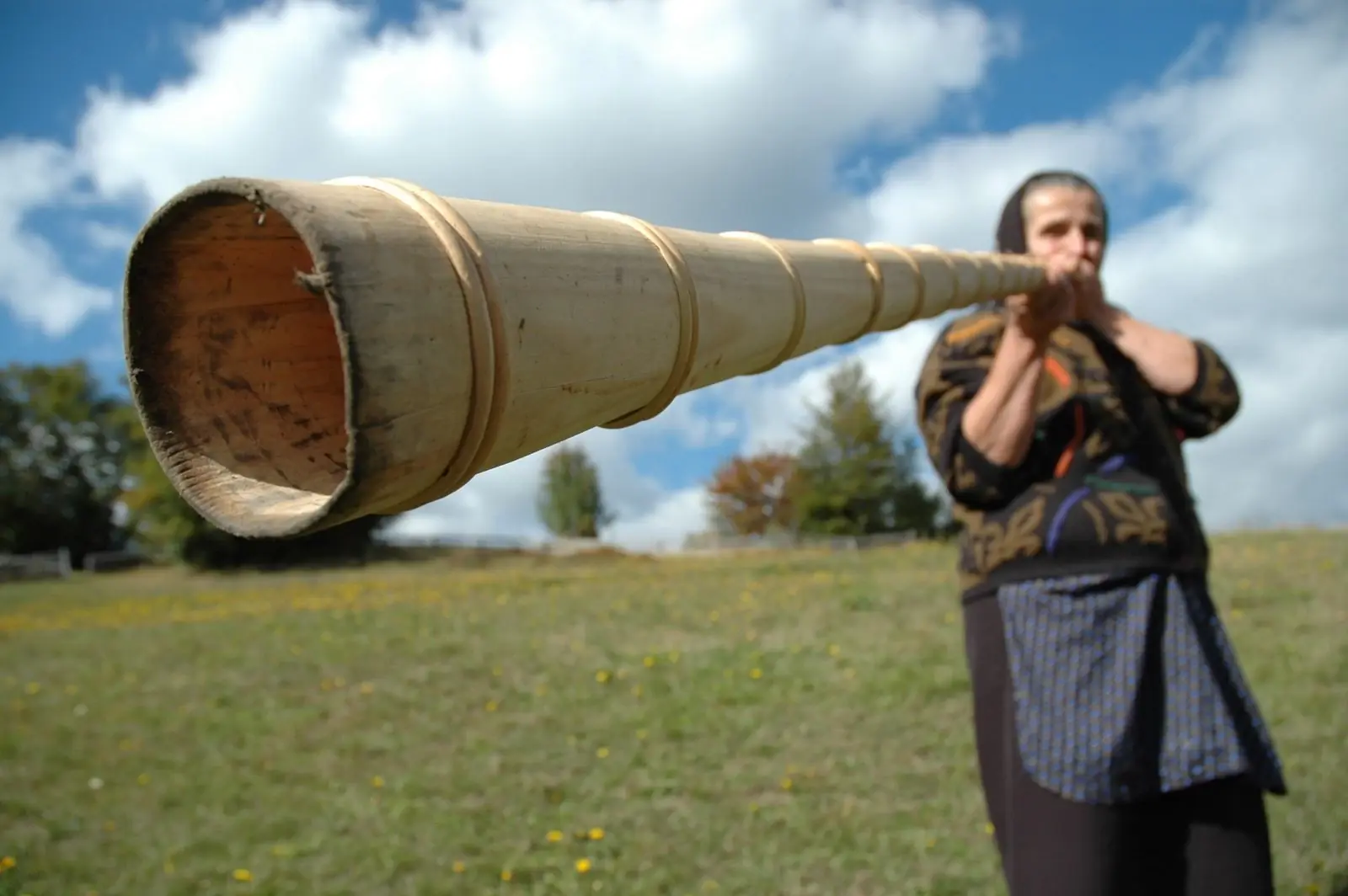 Kayakers paddle in the tranquil waters near a large, eroded rock formation, surrounded by lush greenery and cliffs.
