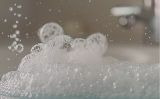 Bulles de savon blanches flottant dans un liquide avec un fond flou.