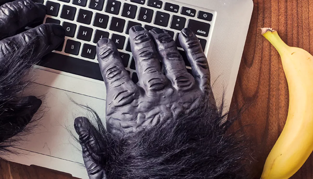 Gorilla hands typing on a keyboard next to a banana