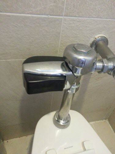 The automatic flush valve controls attached to the plumbing on a toilet