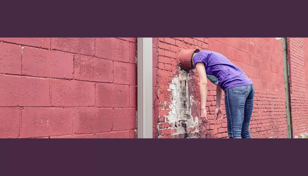 Person banding head against a brick wall