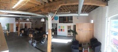 panoramic view of office with wooden ceiling, sitting area, and work stations.
