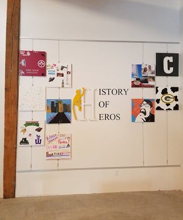 Wall with various artwork pieces, at the center it reads "History of Heros"