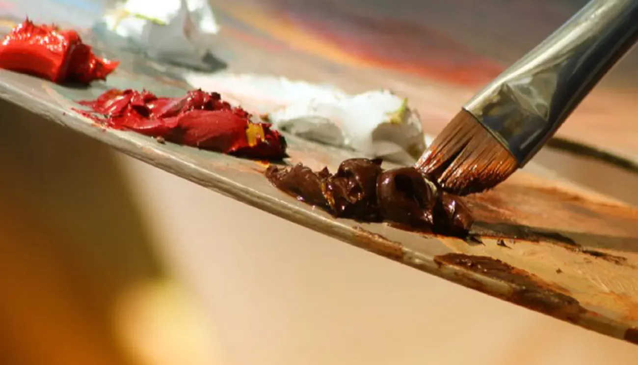 Paintbrush dipping into paint on a palette
