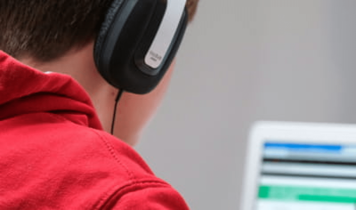 Person wearing headphones and looking at a computer screen.