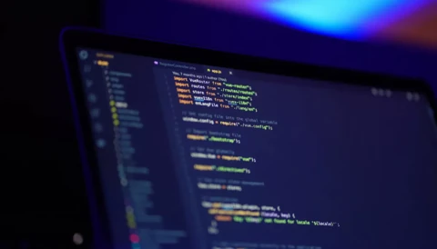Image of code on a computer screen in a dark room.