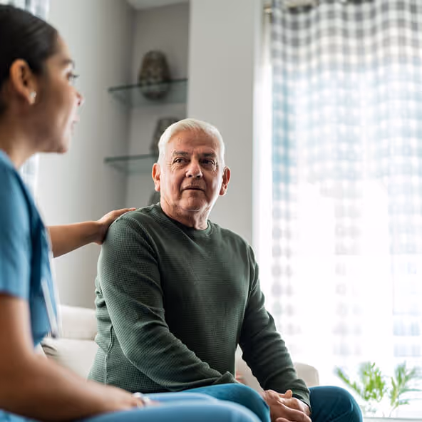 Healthcare professional comforting an older male patient during a consultation