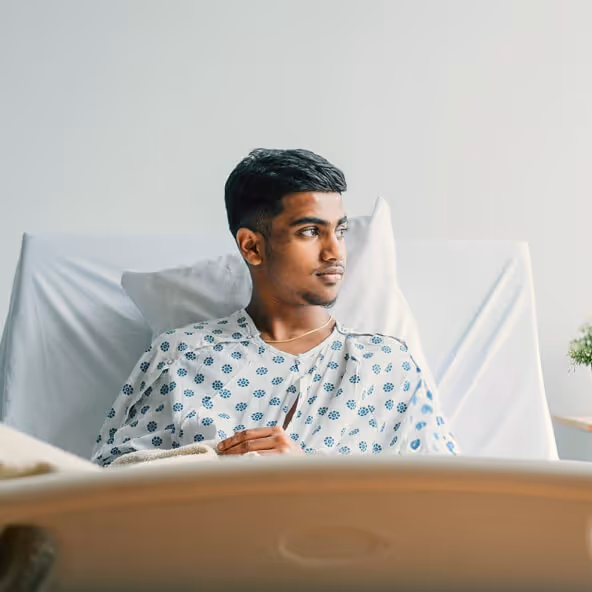Young, male patient resting in a hospital bed receiving medical care