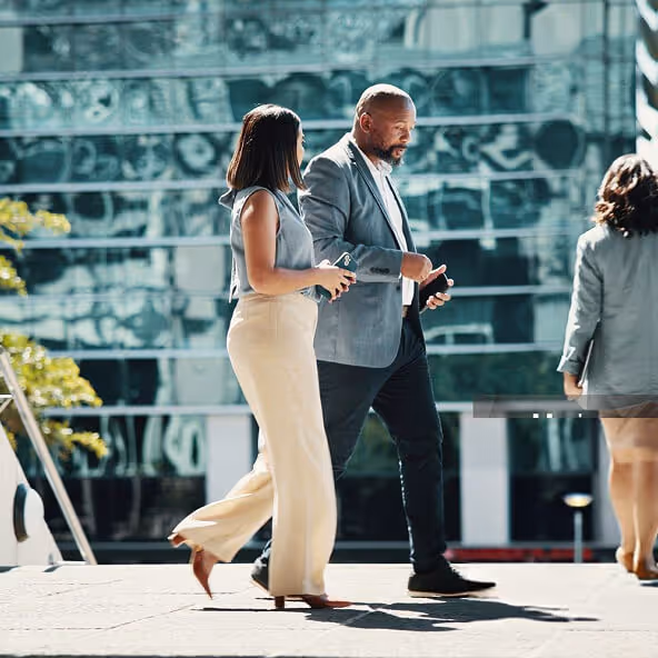 Two professionals walking outside an office building discussing clinical operations