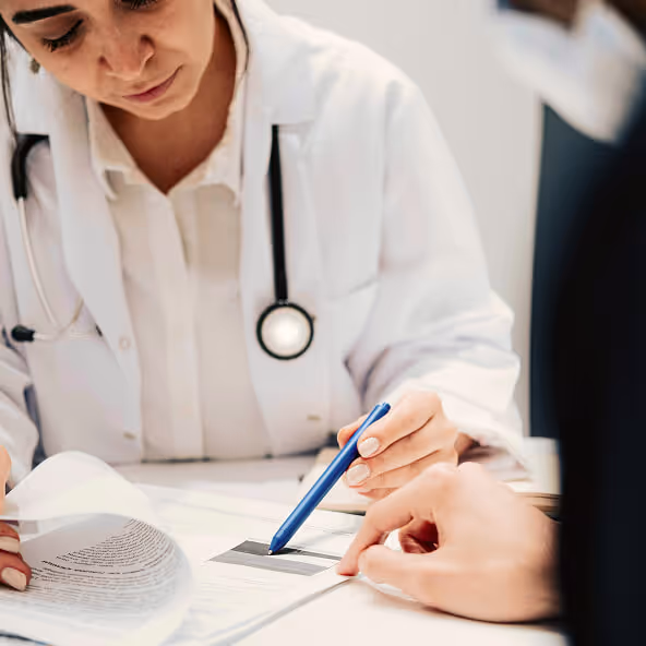 Doctor writing medical notes during a patient consultation