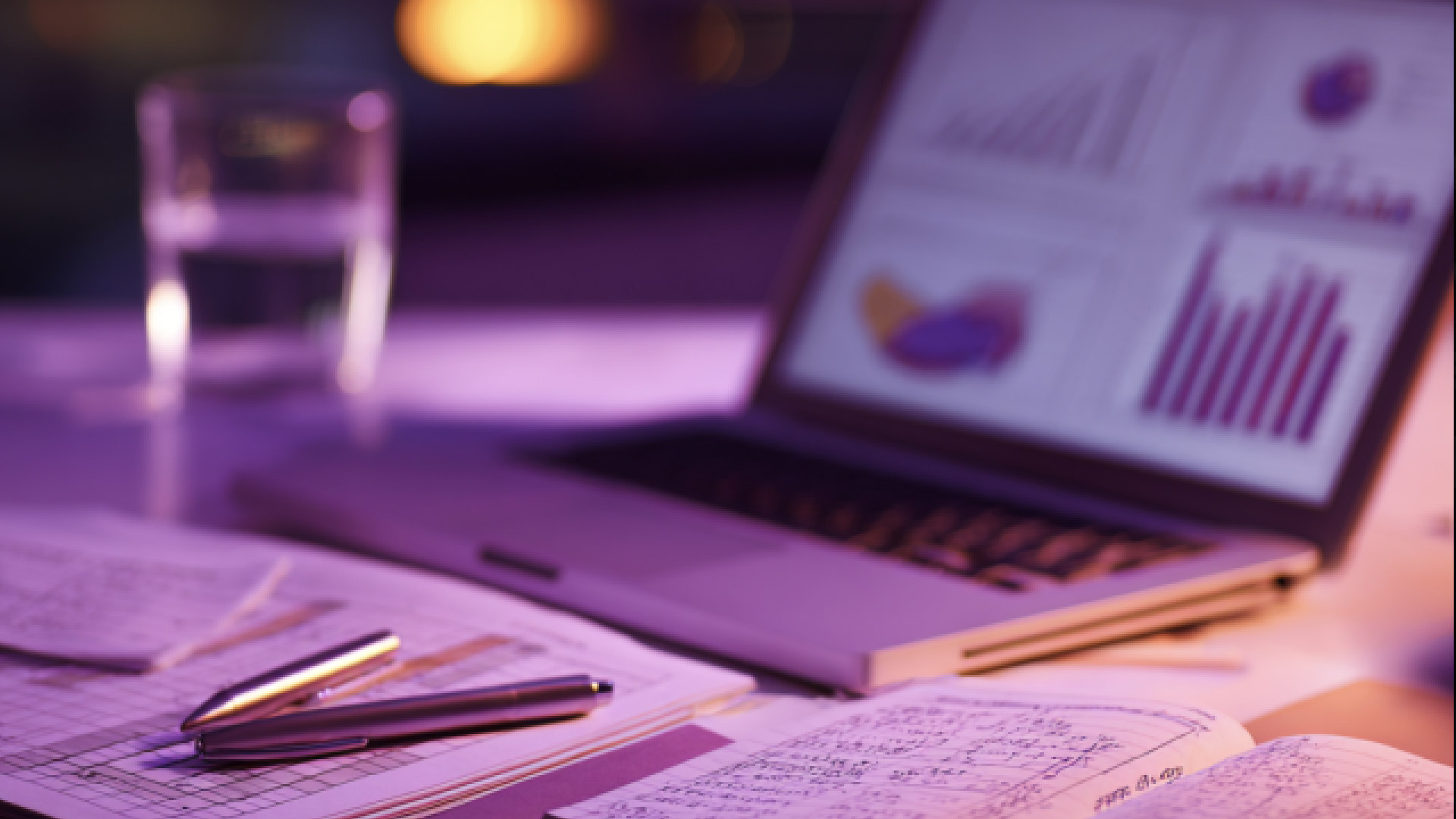 Laptop con grafici e dashboard su scrivania con documenti e penna