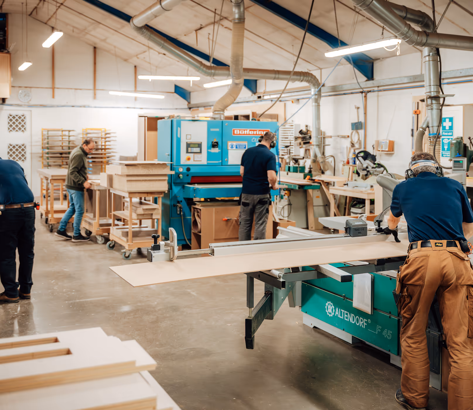 A man is working on a table in a woodworking shop.