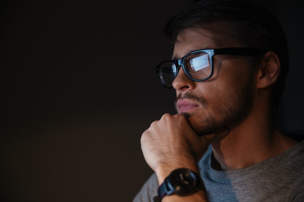 Closeup of focused man in glasses looking at screen