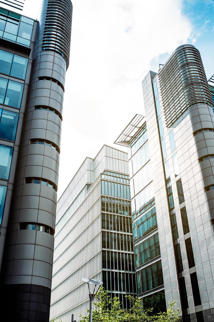 Modern glass and steel office buildings with reflective windows under a bright sky.