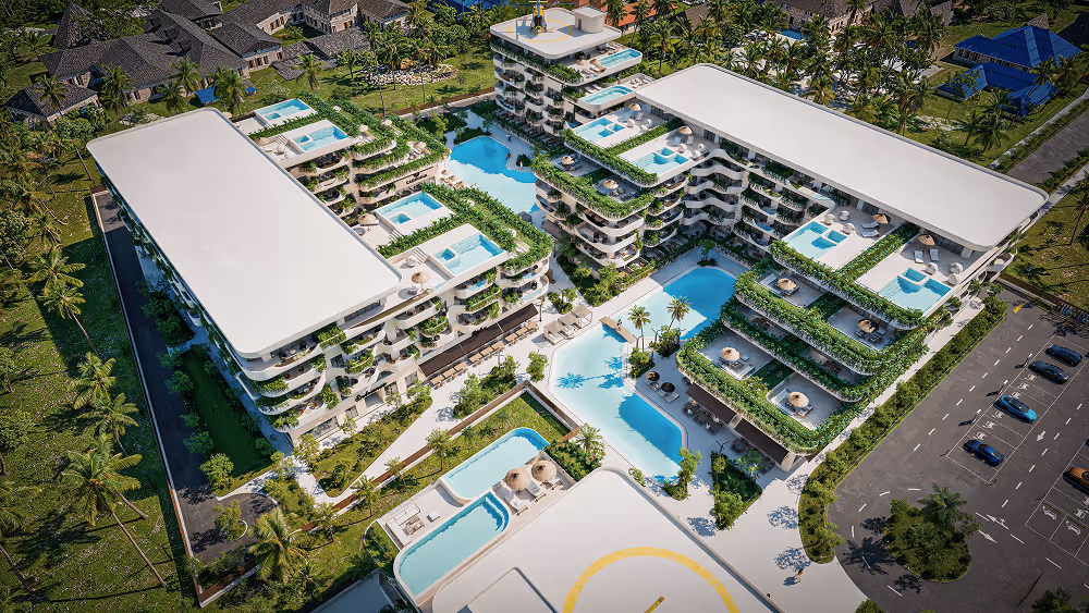 Aerial view of a modern luxury residential complex with multiple buildings featuring rooftop pools, greenery, and a central swimming pool surrounded by palm trees and lounge chairs.