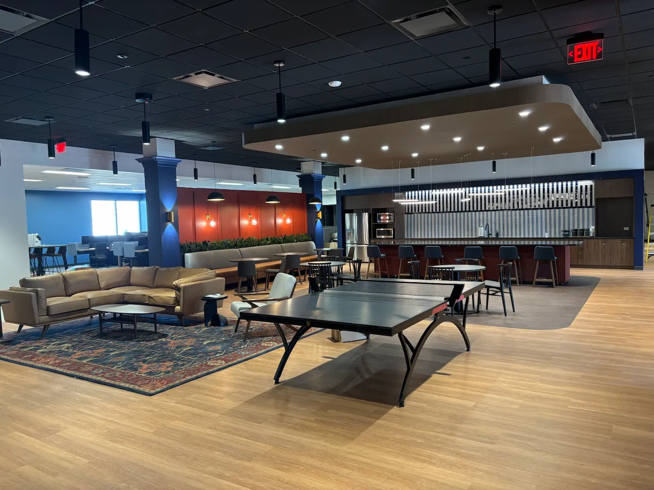 Employee café and dining area at Power HRG, showcasing custom seating, bold brand colors, and a hospitality-inspired layout constructed by Oswald Company.