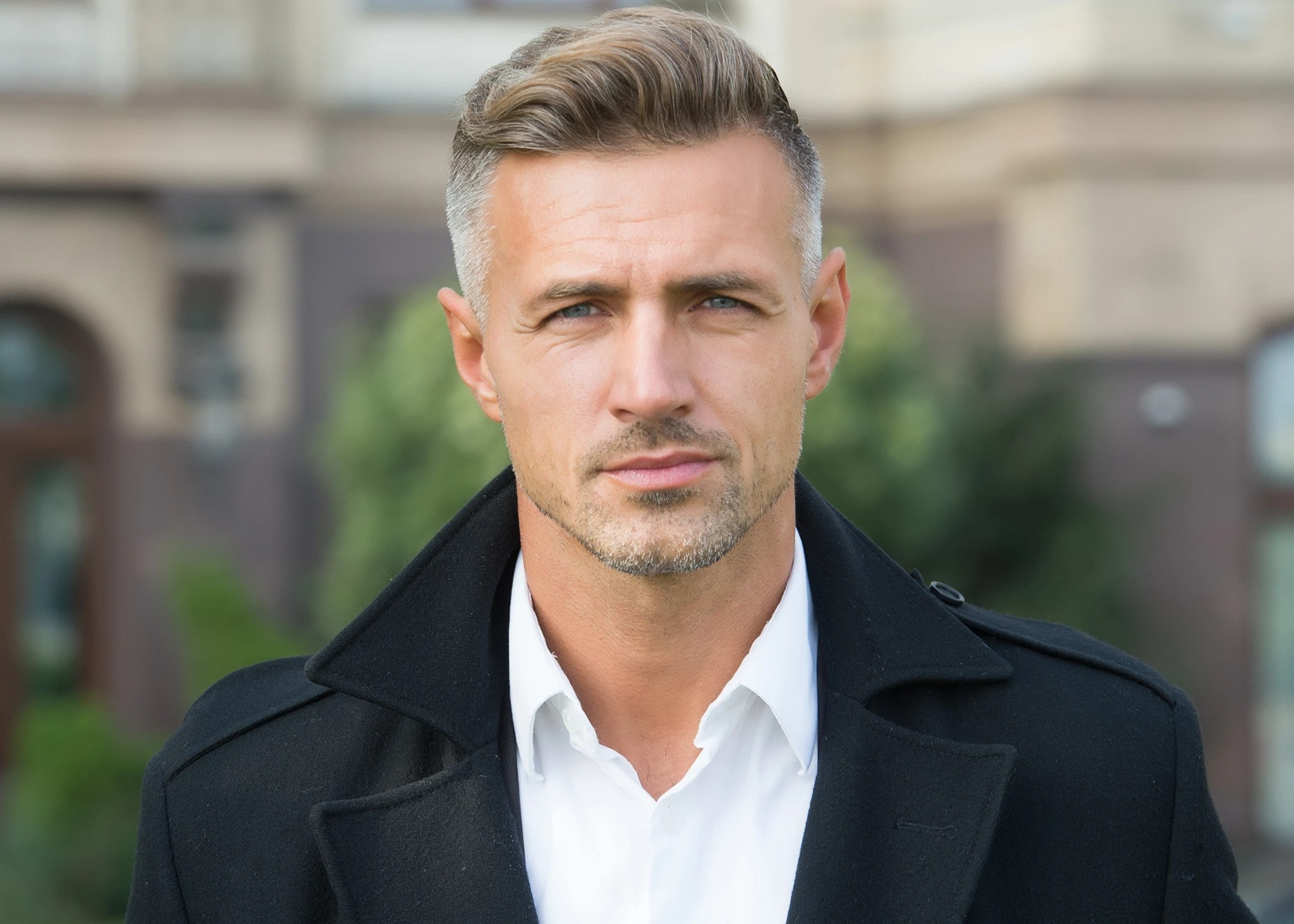 A man wearing a black coat and a white shirt.