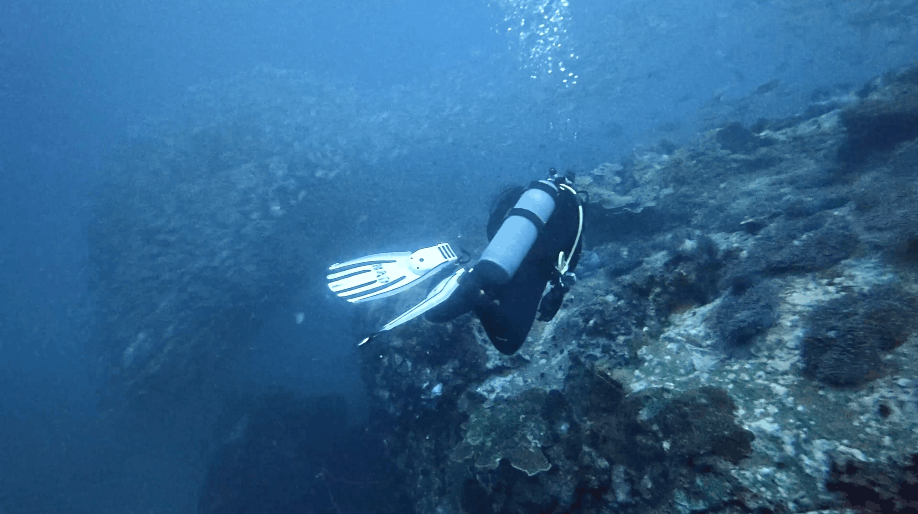 Scuba diver finning along the top of Chumphon Pinnacle, Koh Tao