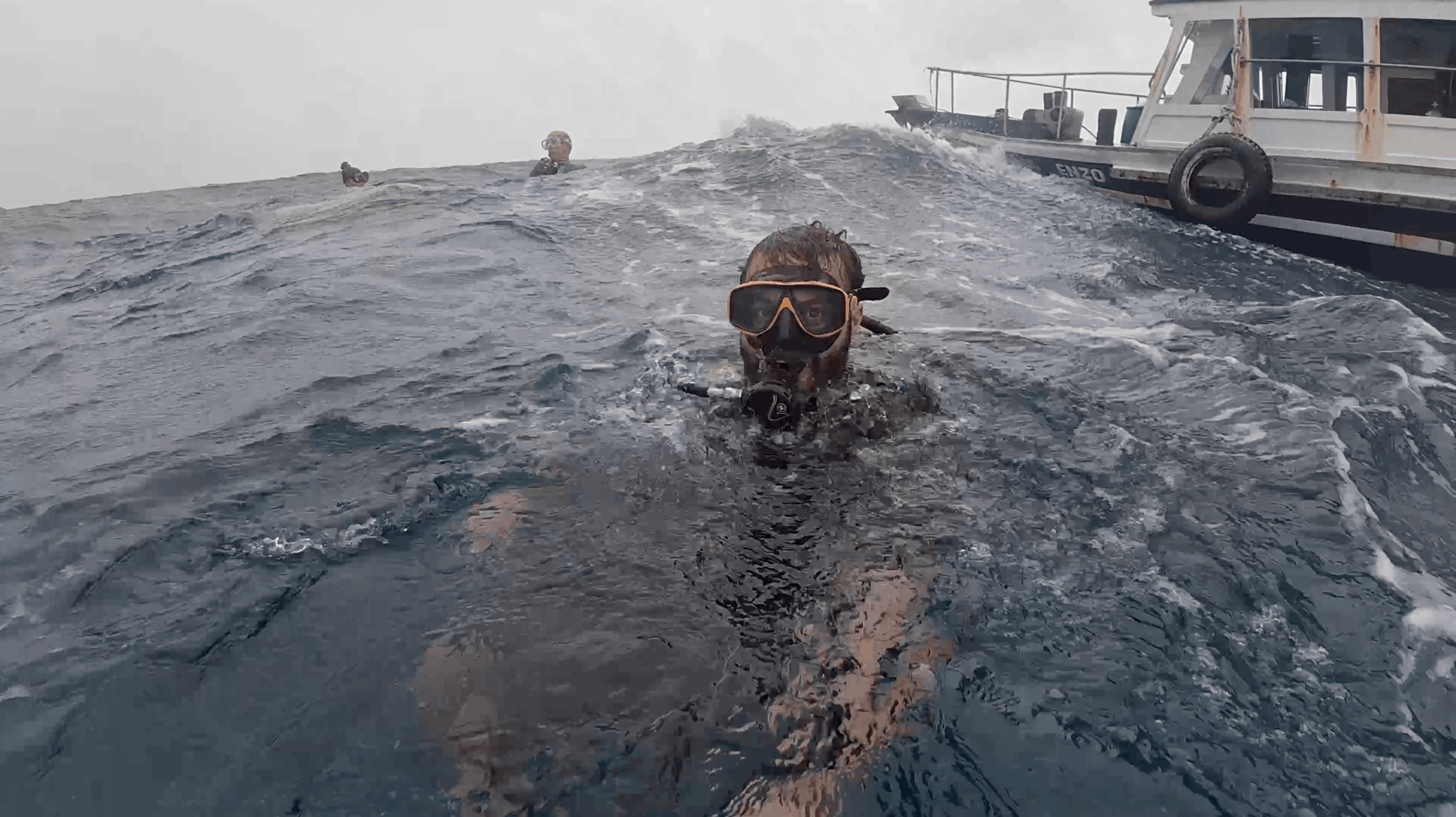 Divemaster Austin at the surface beside the dive boat in choppy water at Chumphon Pinnacle