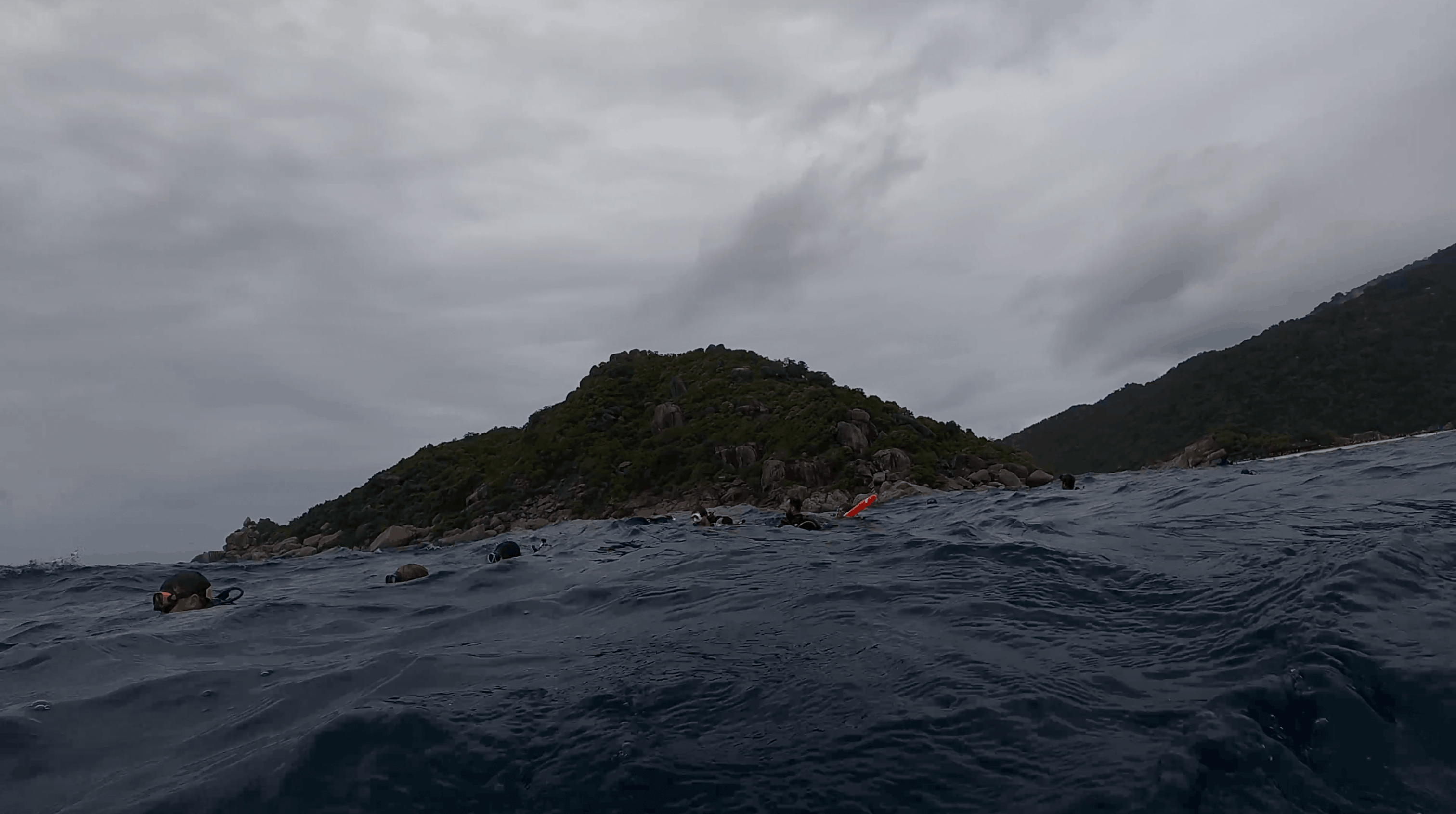 Divers at the surface under heavy cloud beside Koh Tao
