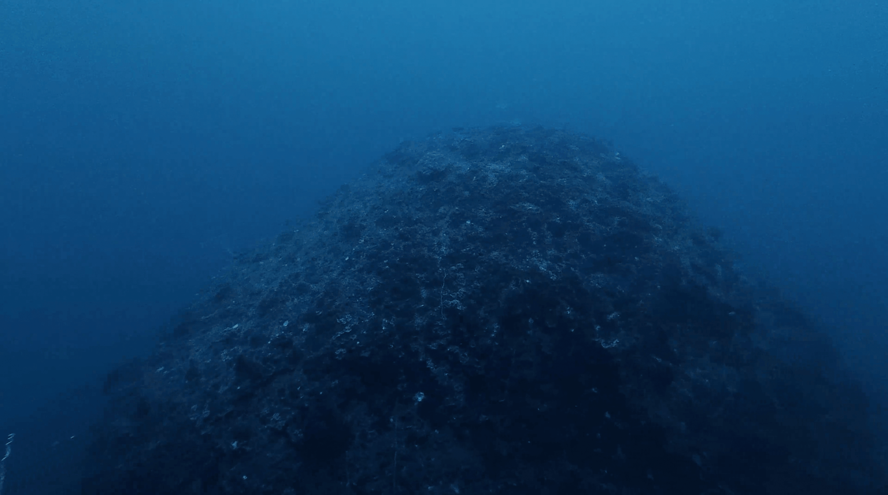 The domed top of the Boulders pinnacle rising out of the blue, Koh Tao
