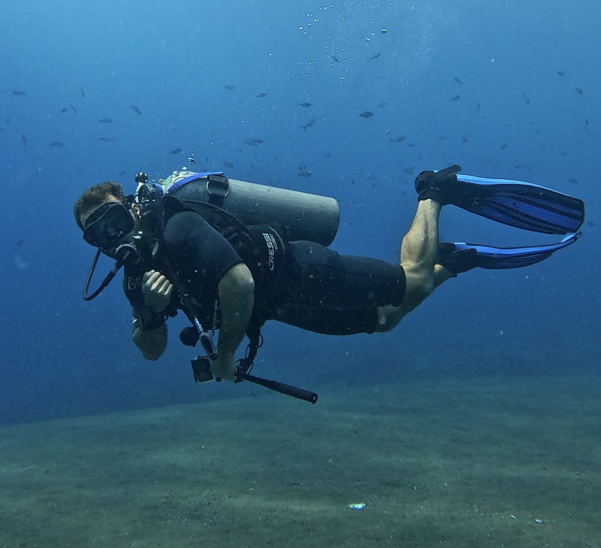 Austin scuba diving in a traditional mask carrying a handheld camera rig