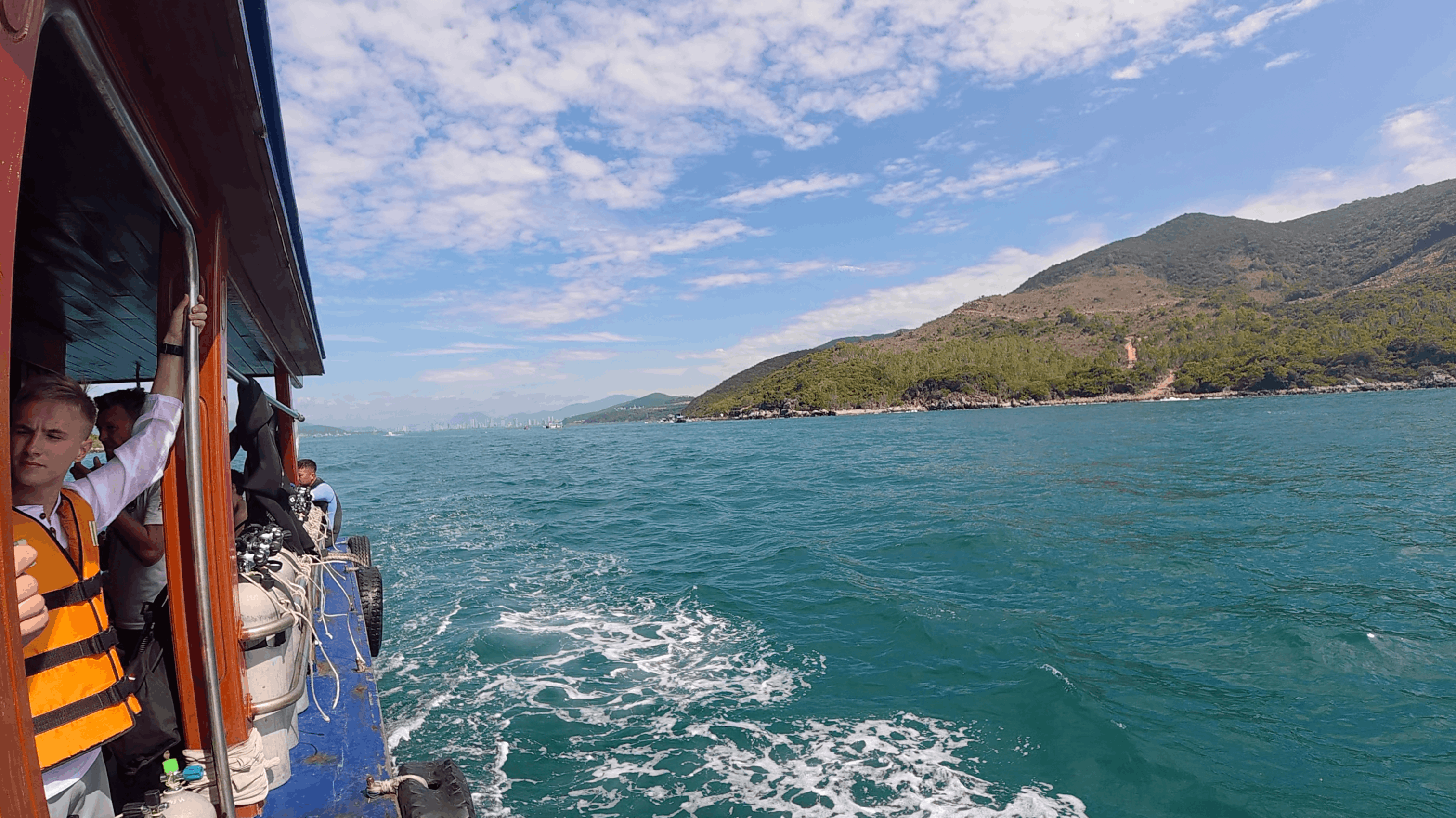 View from the dive boat underway, wake and green island coastline at Dam Bay, Nha Trang, Vietnam