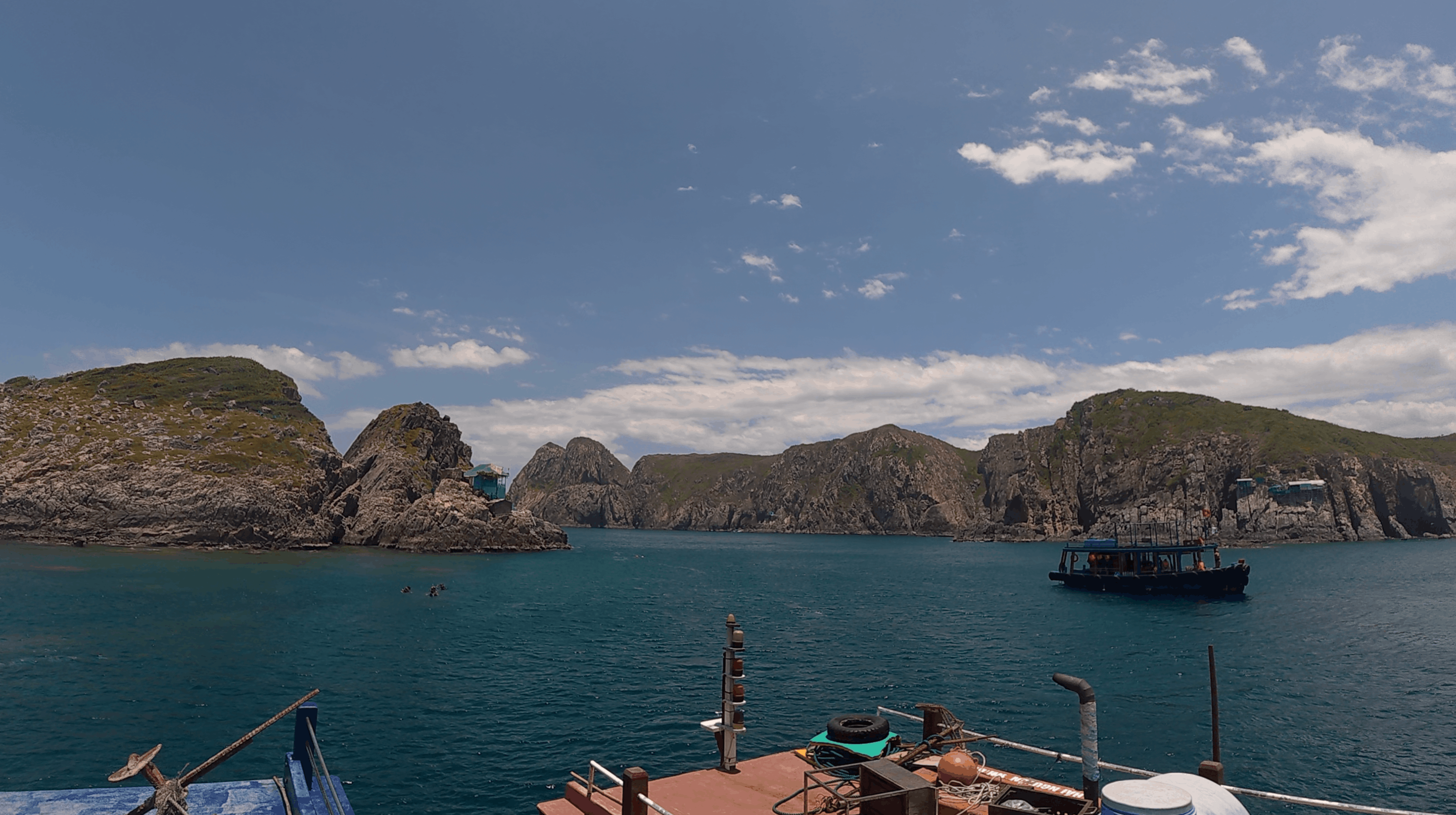 View from the dive boat deck across the rock formations to a second moored dive boat at Madonna Rock, Nha Trang, Vietnam