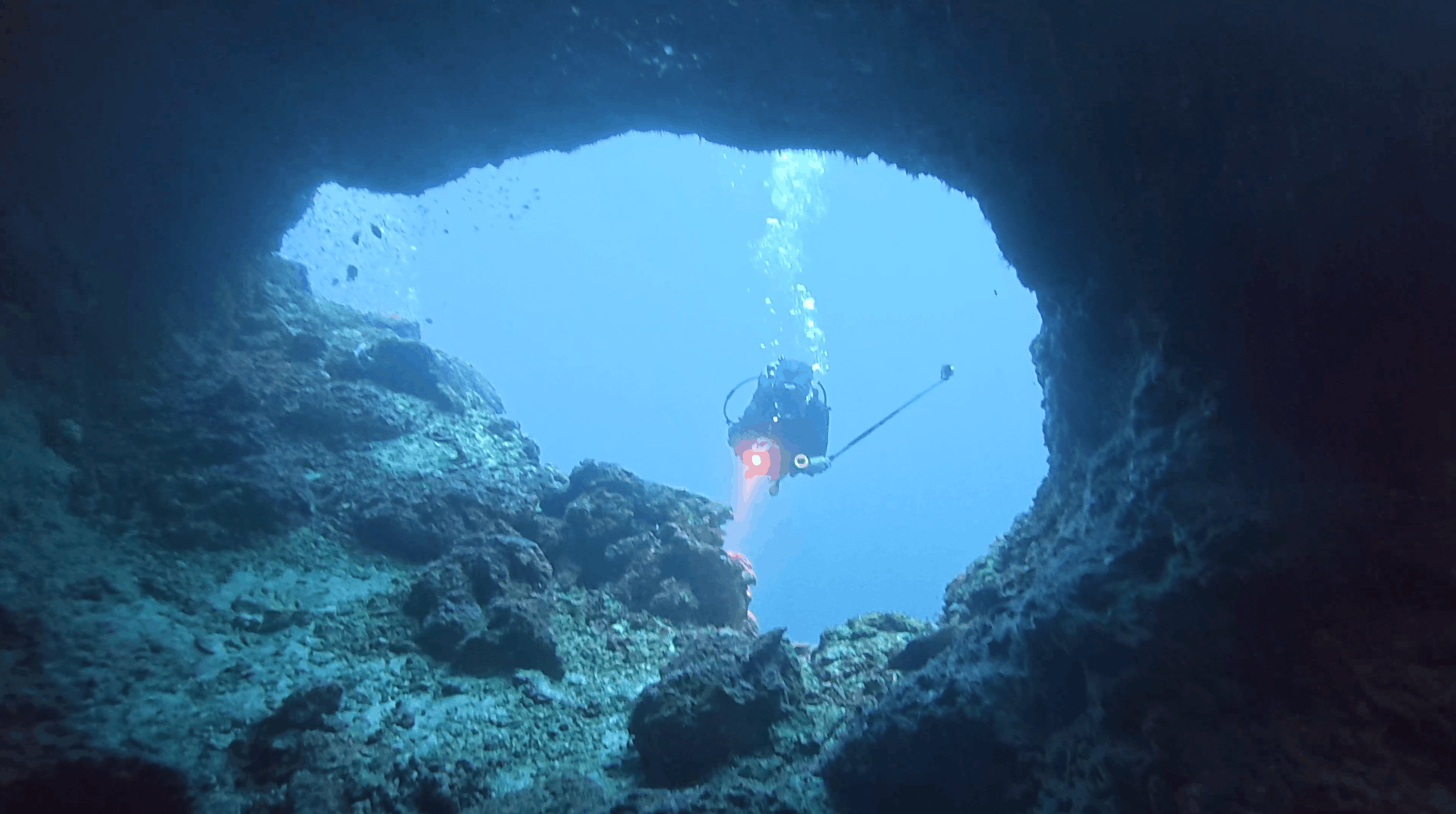 Dive guide Aldrin seen through a rock opening at Pescador Island, Moalboal, Cebu, Philippines