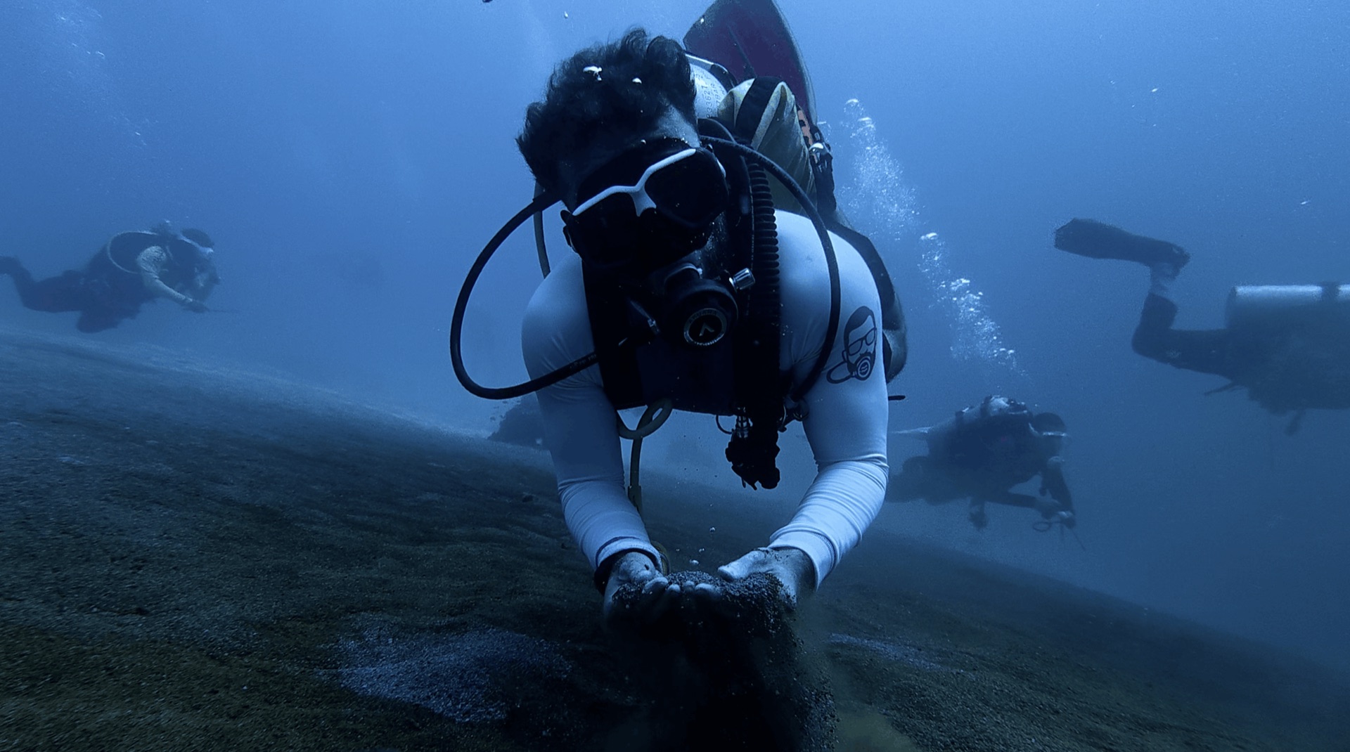 Divemaster Austin pressing his hands into the warm sand at Largahan, Apo Island, Philippines