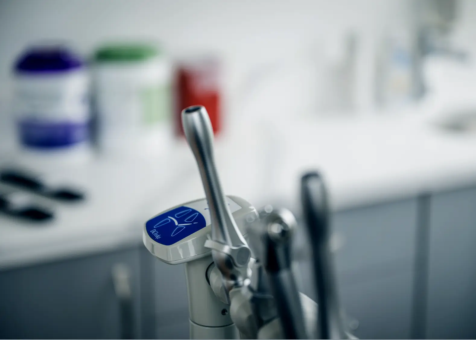 Close-up of a dental tool with a blurred background of dental clinic equipment.