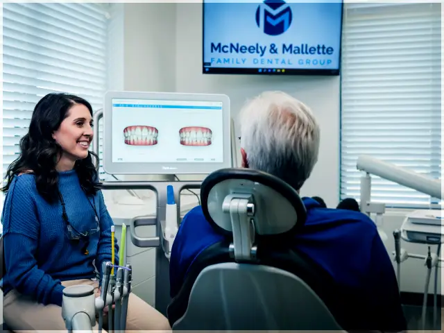 Dentist discussing teeth images displayed on a computer screen with a patient in a dental office.