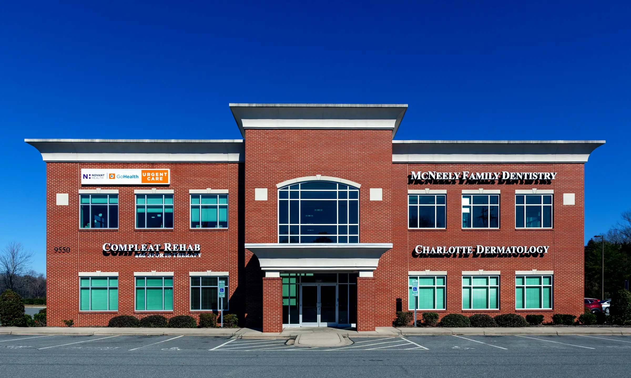 Brick commercial building housing Compleat Rehab, McNeely Family Dentistry, and Charlotte Dermatology under a clear blue sky.