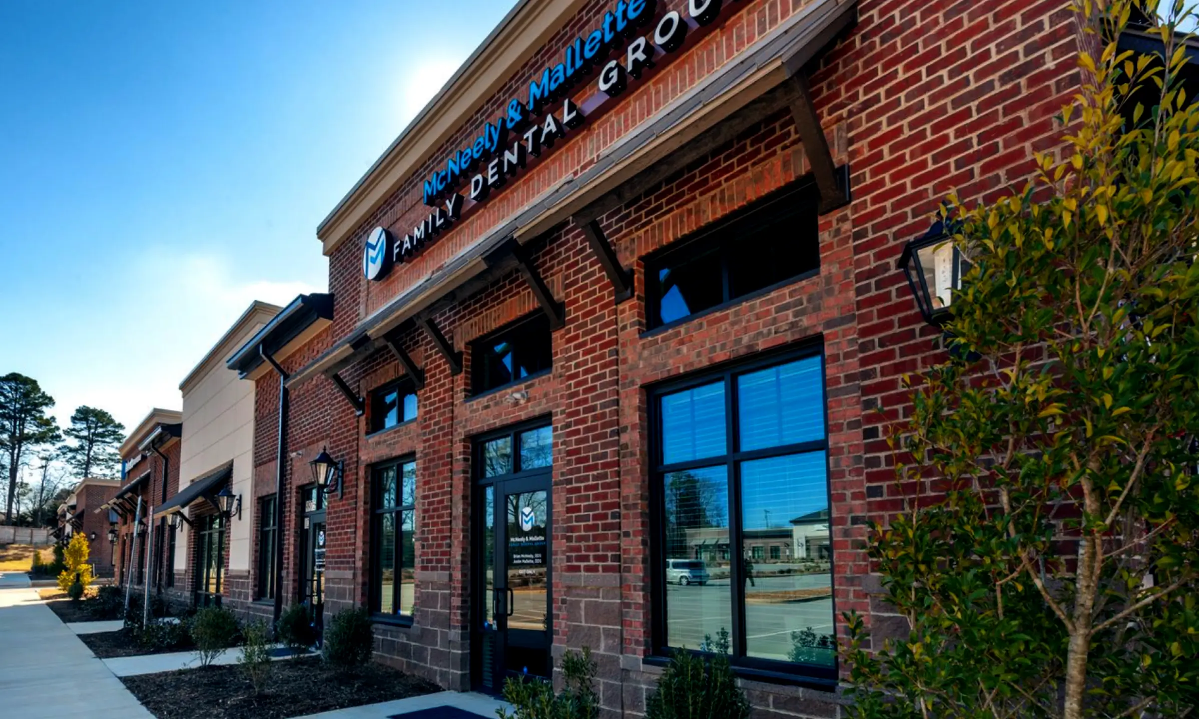 Exterior view of a brick building housing McNeely & Mallette Family Dental Group under a clear sky.