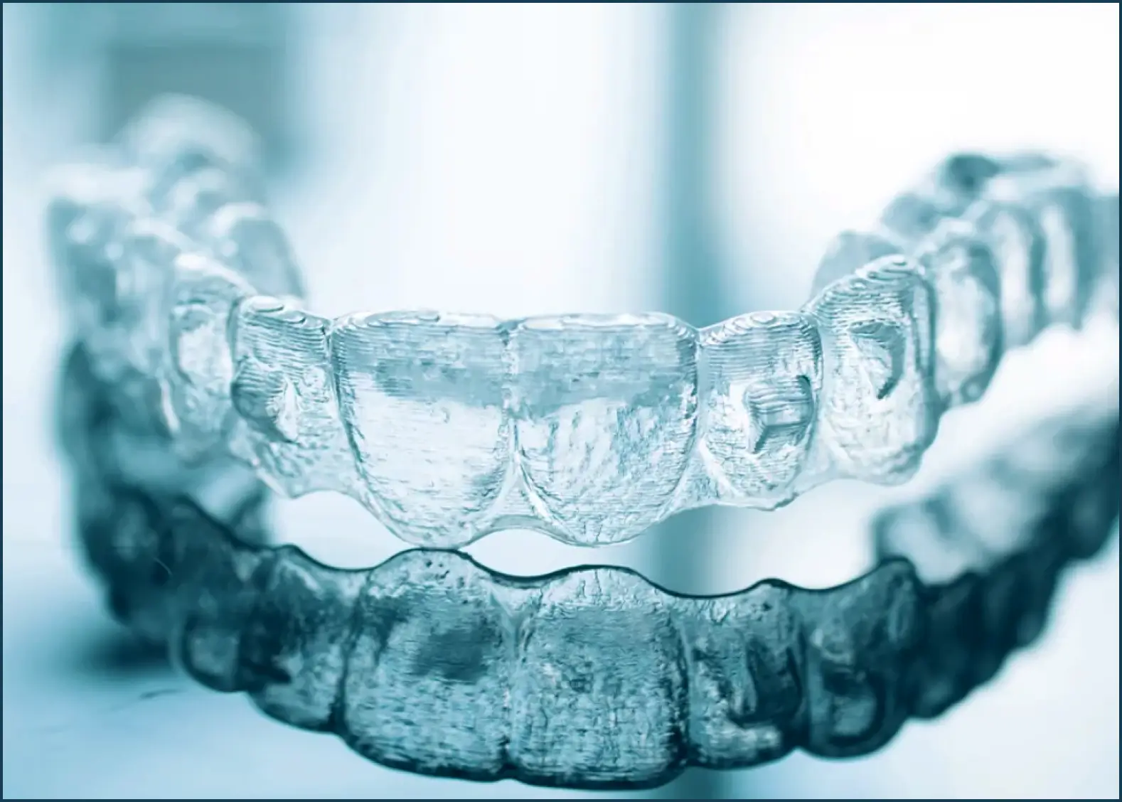Close-up of a clear dental aligner with its reflection below.