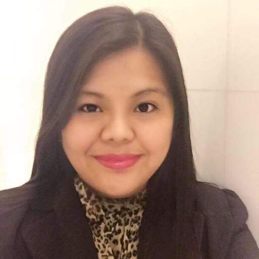 Smiling woman with long dark hair wearing a black blazer and leopard print top against a light background.