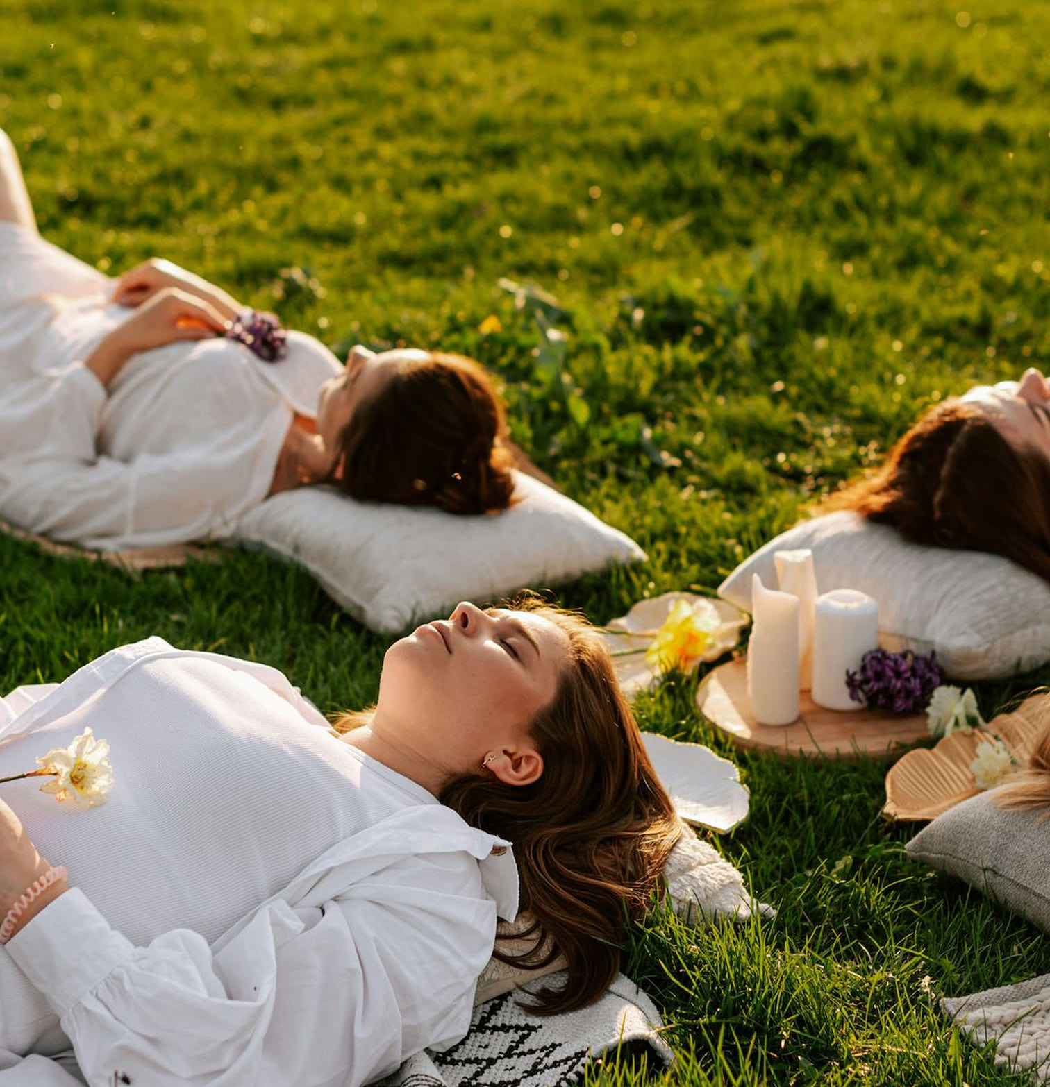 Group of women laying on pillows in grass