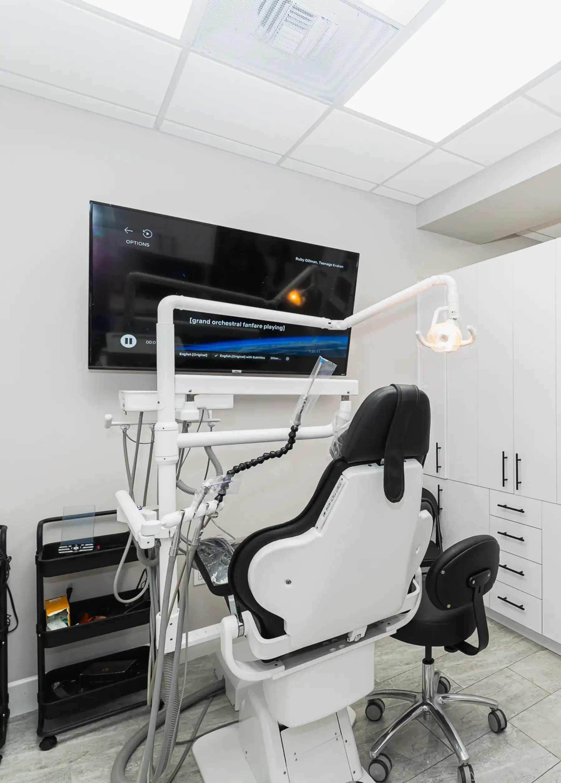 A dentist chair in a room with a flat screen tv.